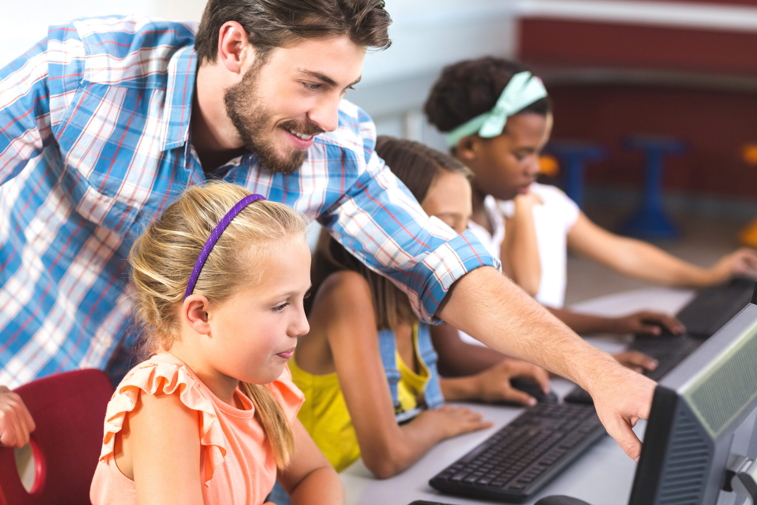 A teacher guides students in using computers in the classroom.